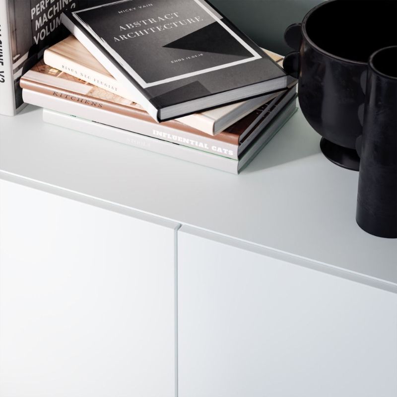 Stack of books on a white surface with a black mug next to them