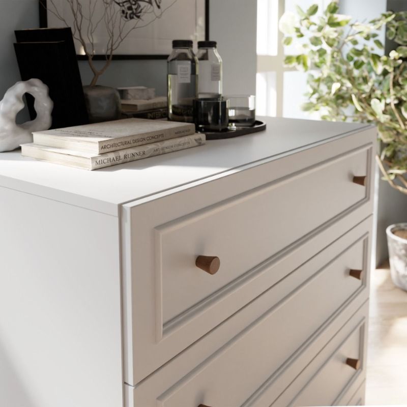 White dresser with wooden knobs in a room with decor elements.