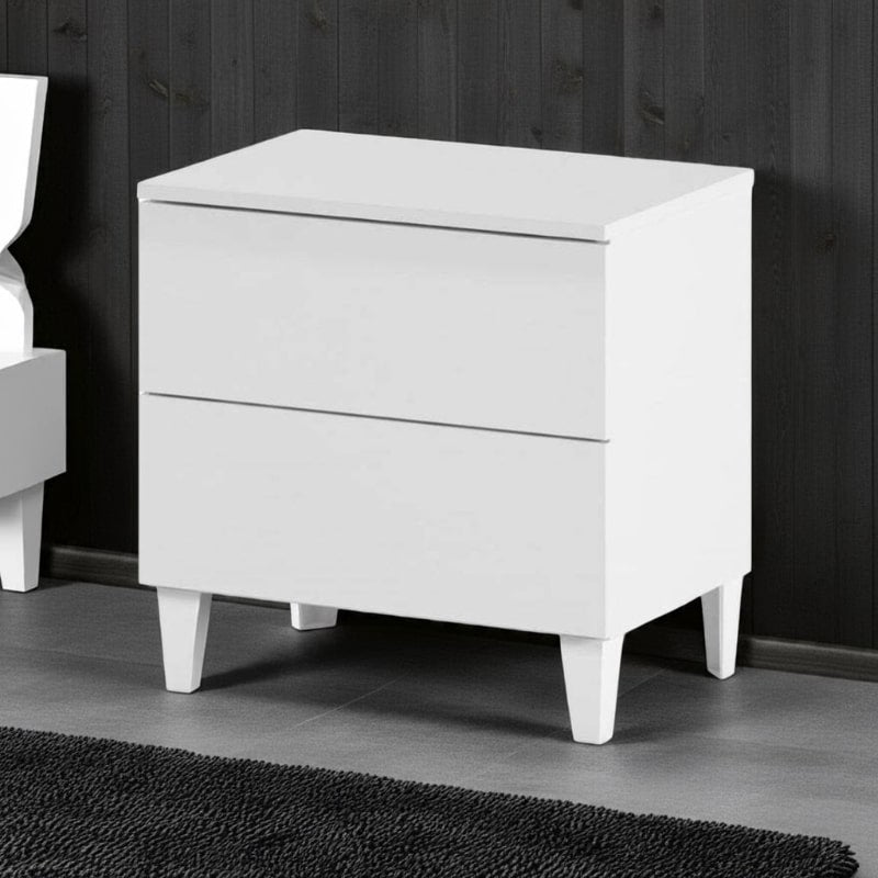 White nightstand with two drawers against a dark wooden wall.
