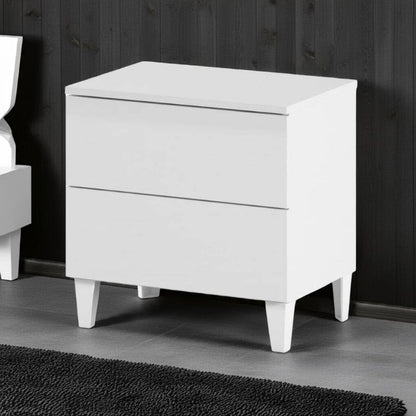 White nightstand with two drawers against a dark wooden wall.
