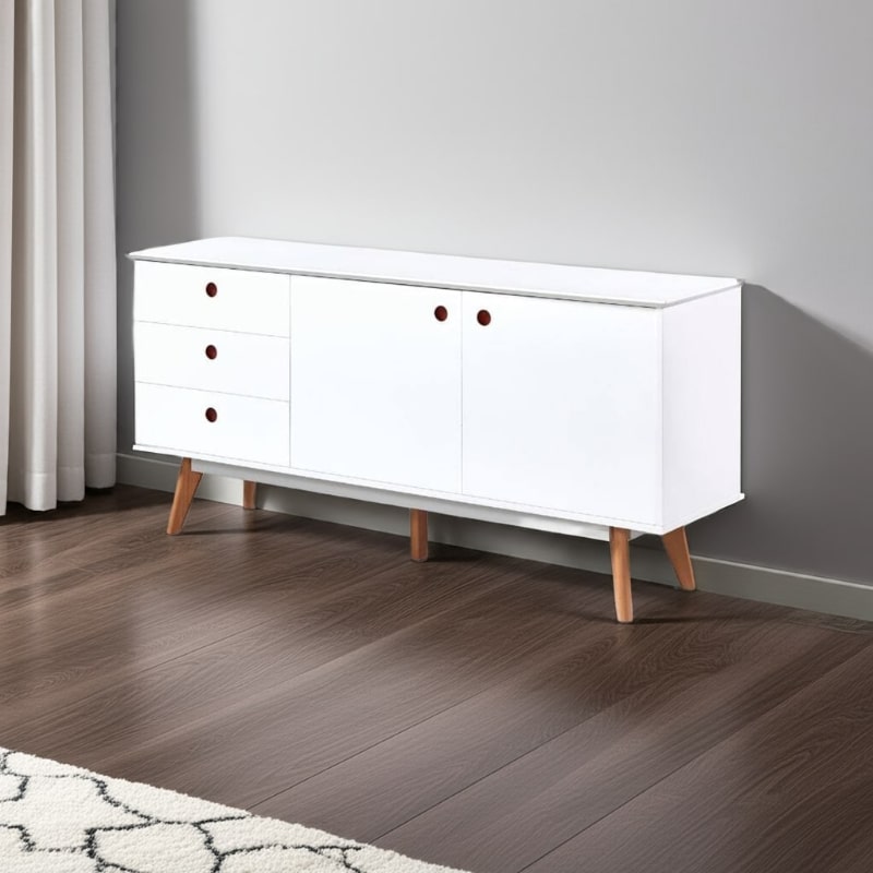 White dresser with wooden legs on a wooden floor against a gray wall