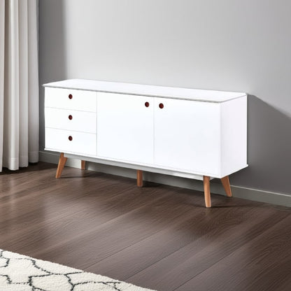 White dresser with wooden legs on a wooden floor against a gray wall
