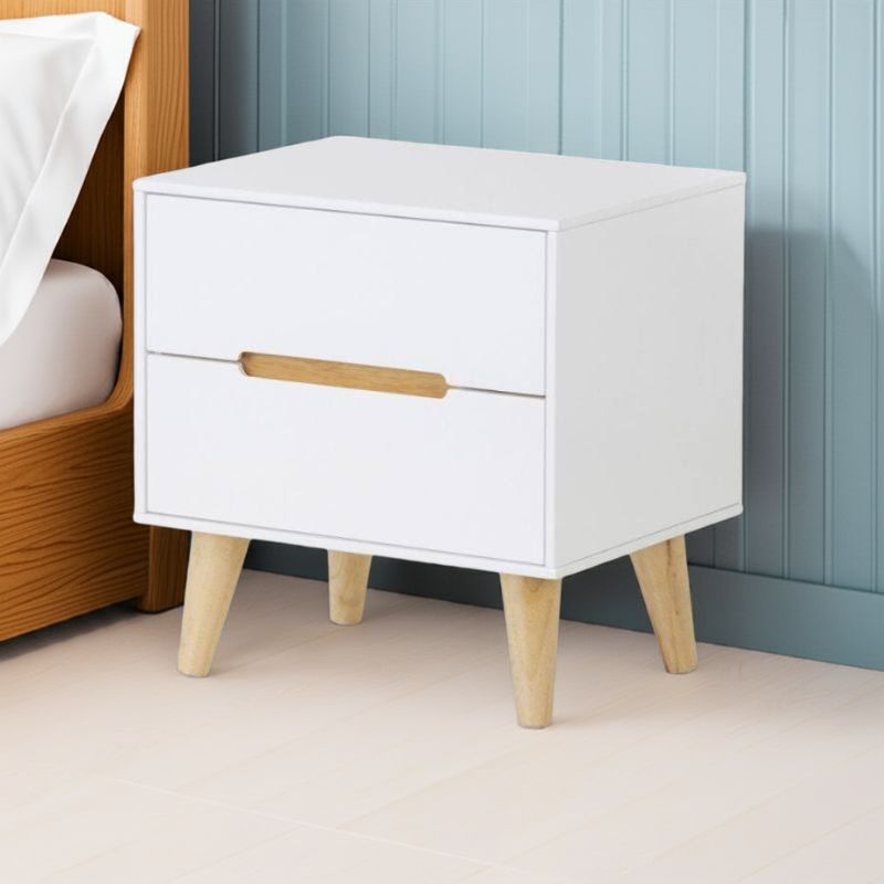 White nightstand with wooden legs and handle against a blue wall.