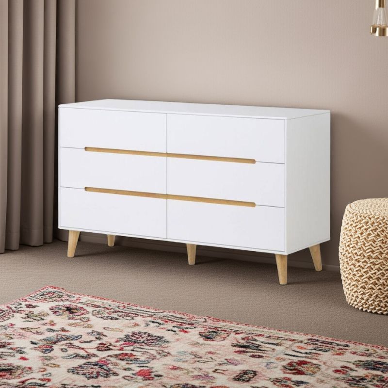 White dresser with gold handles in a room with a floral rug and beige ottoman.
