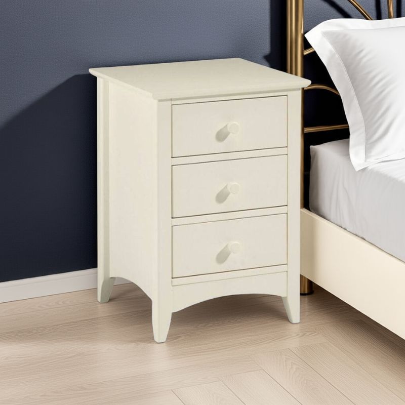 White nightstand with three drawers next to a bed in a bedroom setting.