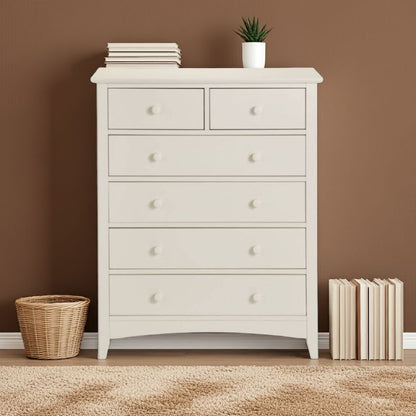 White dresser with five drawers against a brown wall, with books and a plant on top.