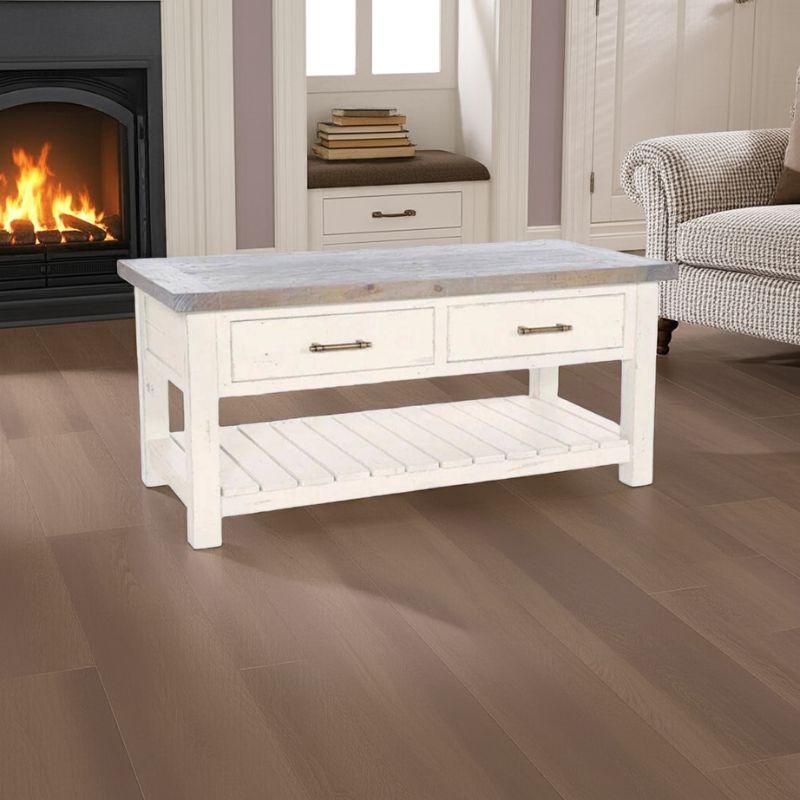 White coffee table with a gray top in a living room setting with a fireplace and armchair.