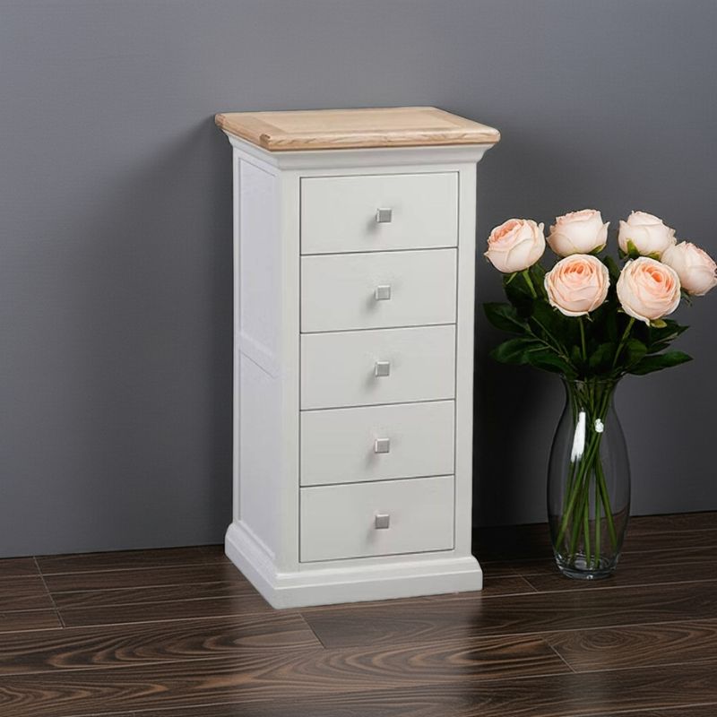 White wooden dresser with four drawers next to a vase of flowers on a dark wooden floor.