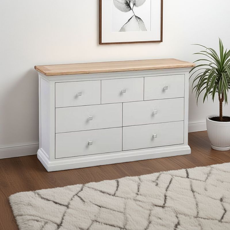 White dresser with wooden top in a room with a plant and framed picture.