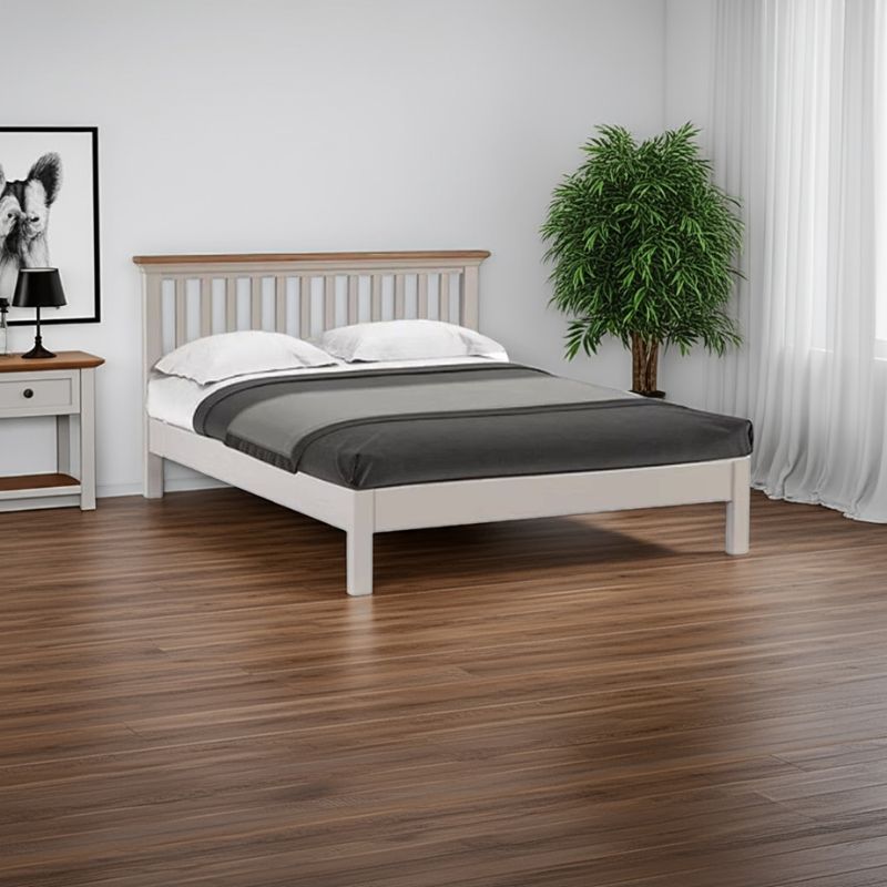 Wooden bed with white bedding in a room with a plant and side table.