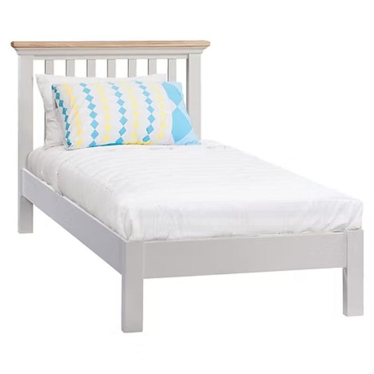 White bed with wooden headboard and striped pillow.