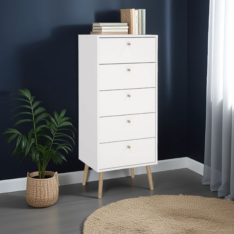 White dresser with wooden legs and 5 drawers in a room with a dark blue wall, plant, and rug.