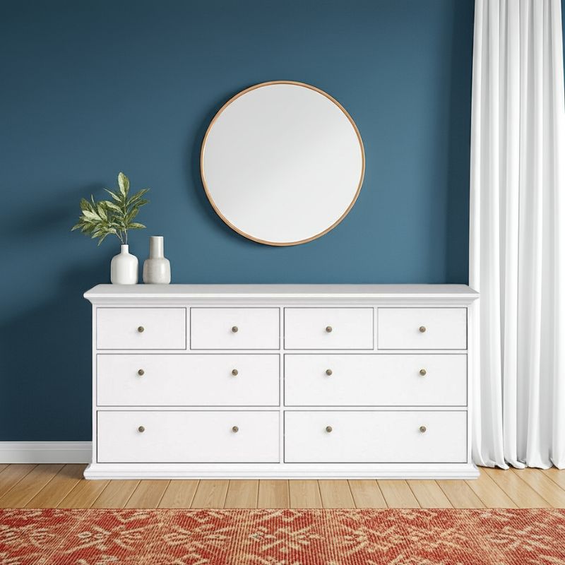 White dresser with round mirror against a blue wall