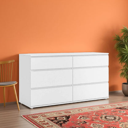 White dresser against an orange wall with a chair and plant in the foreground