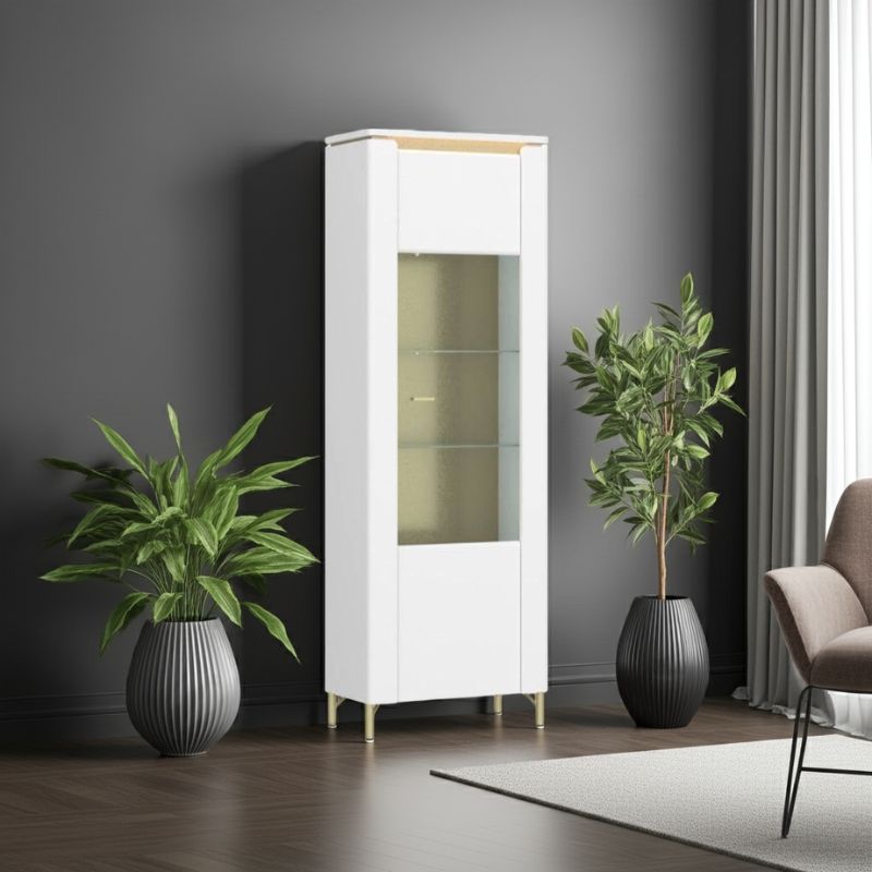White display cabinet with glass doors in a room with plants and a chair.