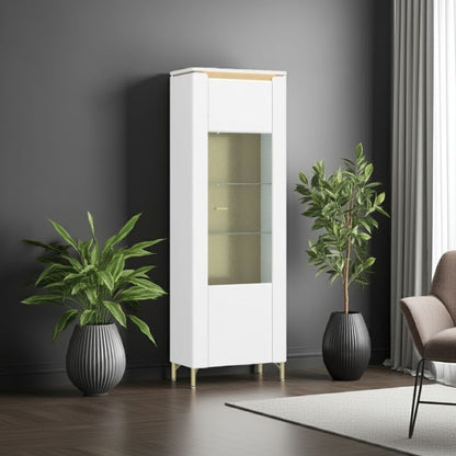 White display cabinet with glass doors in a room with plants and a chair.