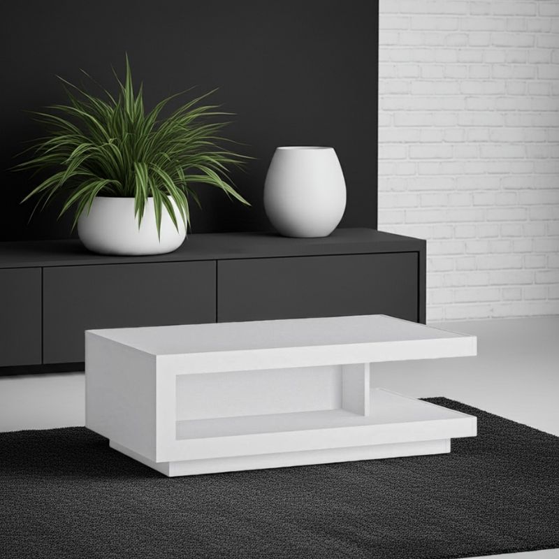 Modern white coffee table with a black cabinet and plant in a room.