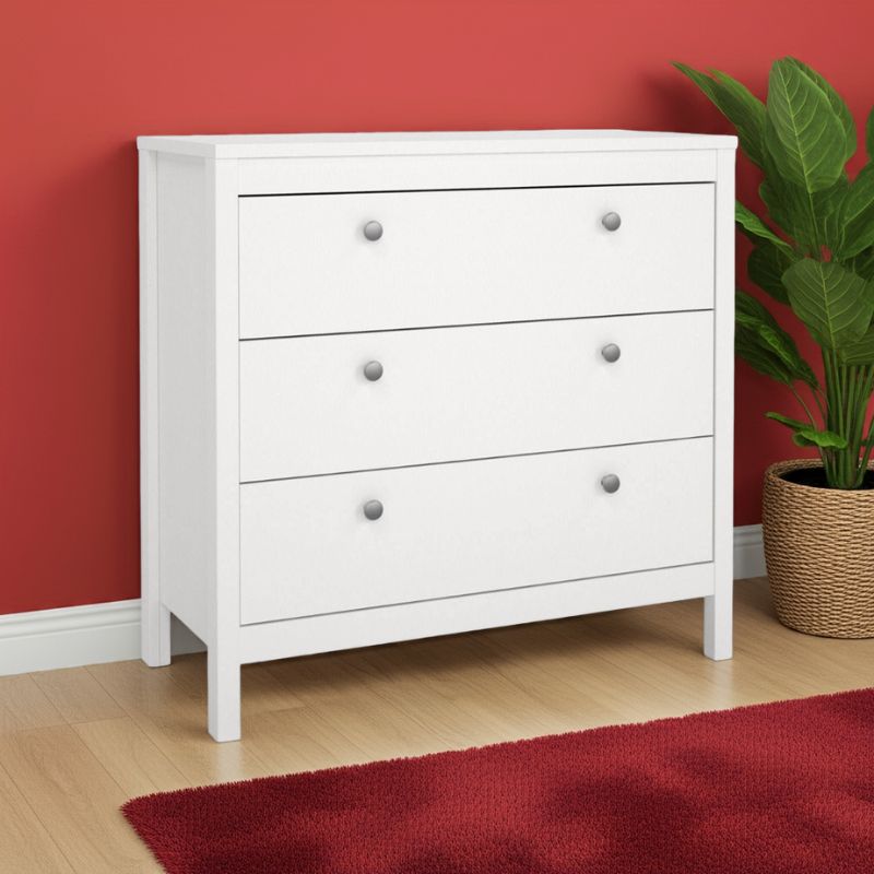 White dresser with three drawers against a red wall with a plant on a red rug.