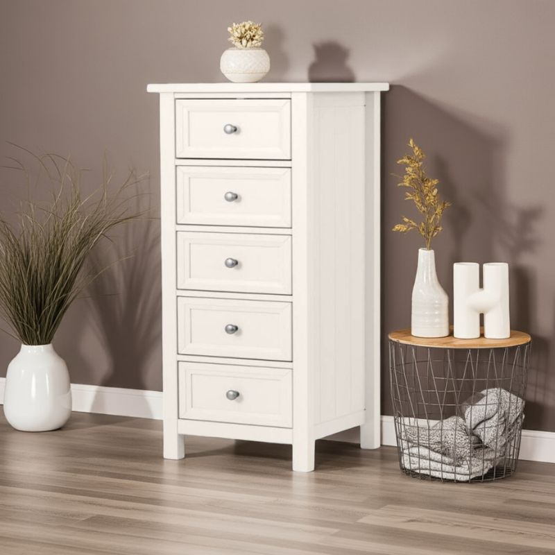White wooden chest of drawers with decorative items in a room setting.