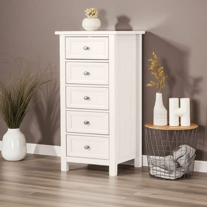 White wooden chest of drawers with decorative items in a room setting.