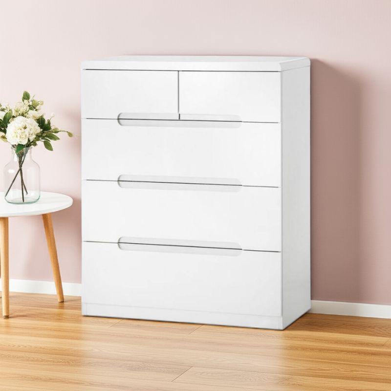 White dresser with four drawers in a room with a pink wall and wooden floor.