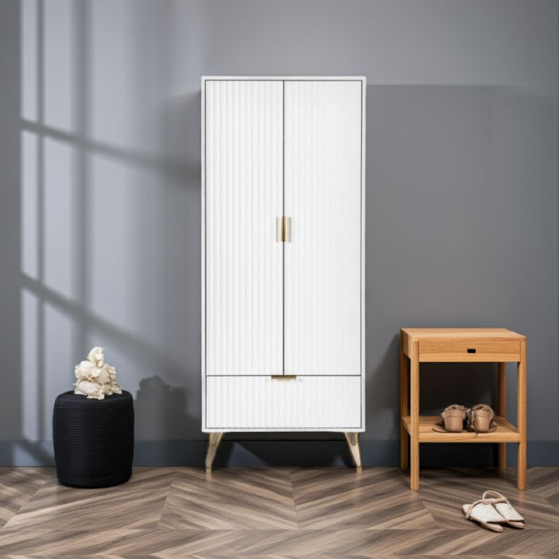 White cabinet with gold handles next to a wooden side table against a gray wall.
