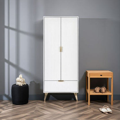 White cabinet with gold handles next to a wooden side table against a gray wall.