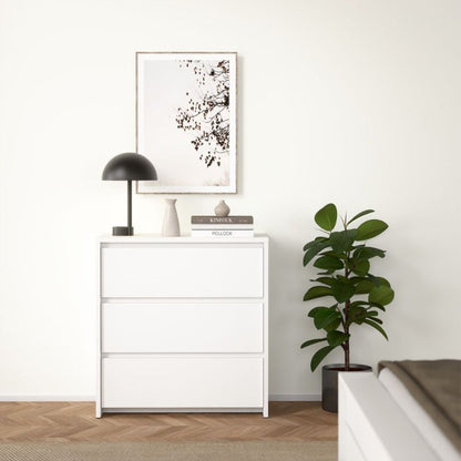 White dresser with decorative items and a plant in a minimalistic room.