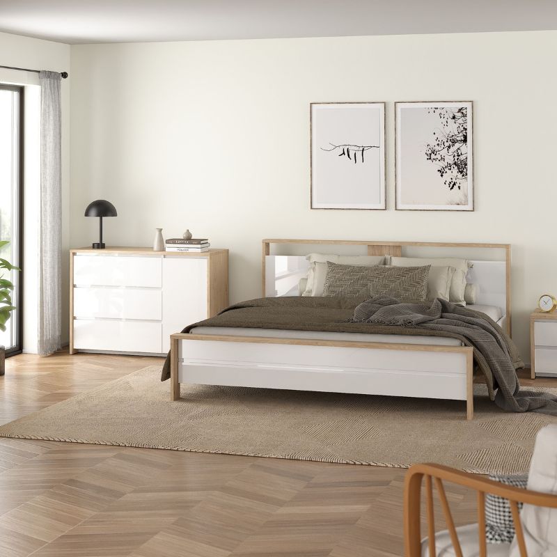 Modern bedroom with a bed, dresser, and framed artwork on the wall.