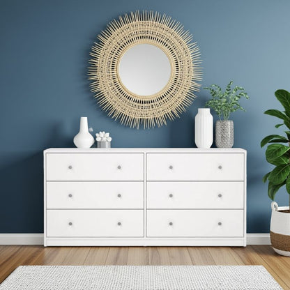 White dresser with 6 large drawers with decorative items against a blue wall