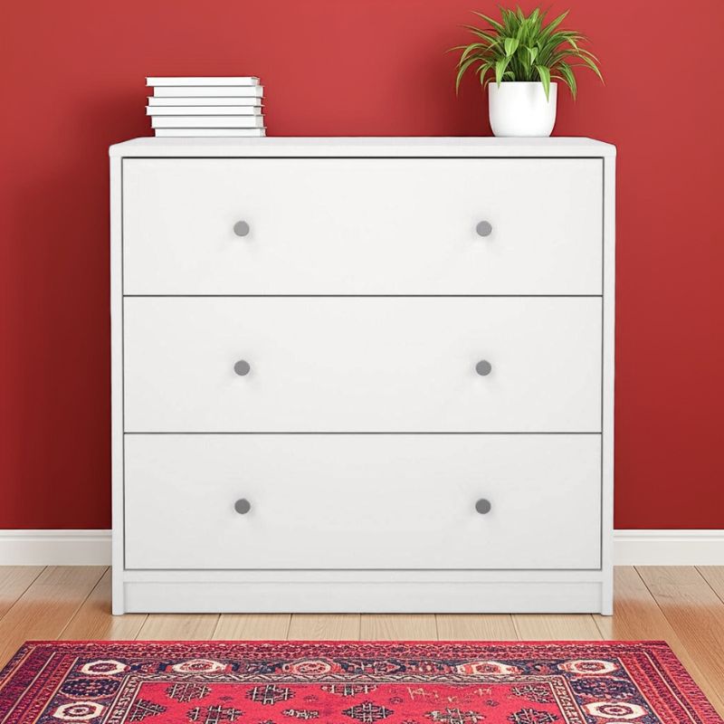 White dresser with three drawers against a red wall with a plant on top