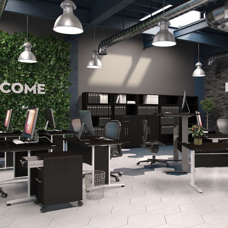 Modern office interior with desks, computers, and a 'Welcome' sign.