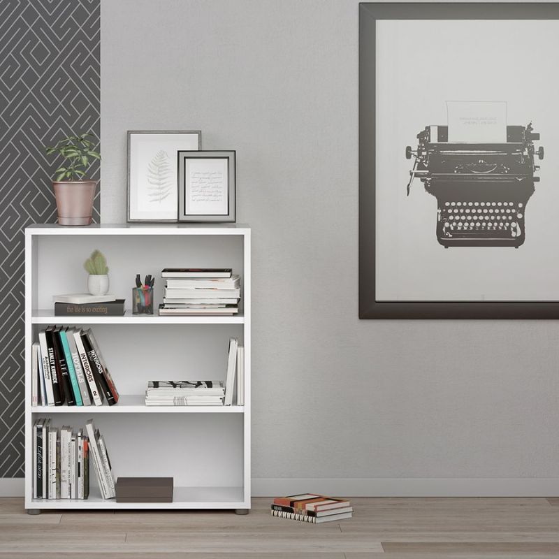 White bookshelf with books and decorative items against a gray wall with a framed typewriter print.