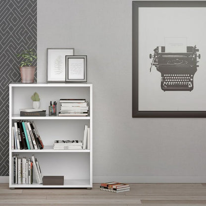 White bookshelf with books and decorative items against a gray wall with a framed typewriter print.
