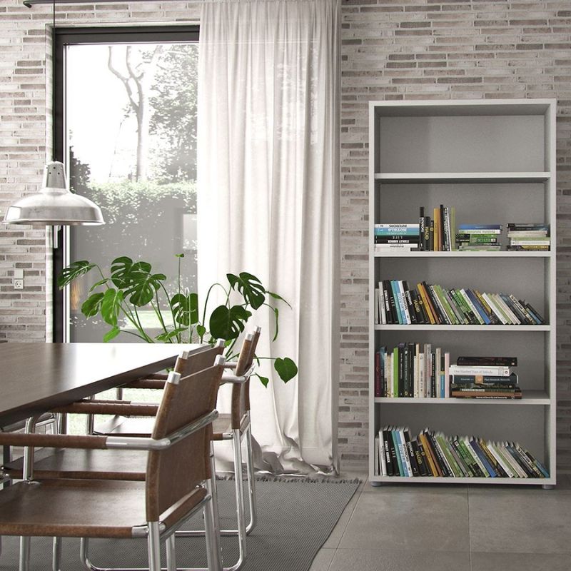 Modern interior with a dining table, chairs, and a bookshelf against a brick wall.