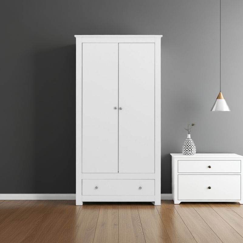 White wardrobe and nightstand against a gray wall with a pendant light.