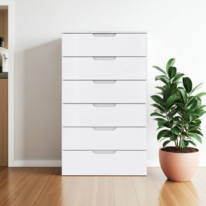 White dresser with multiple drawers next to a potted plant on a wooden floor.
