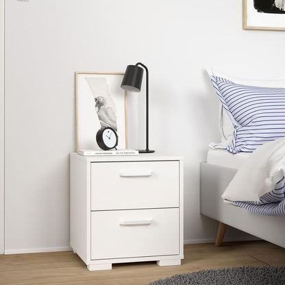 White nightstand with a lamp and clock next to a bed with striped pillows.