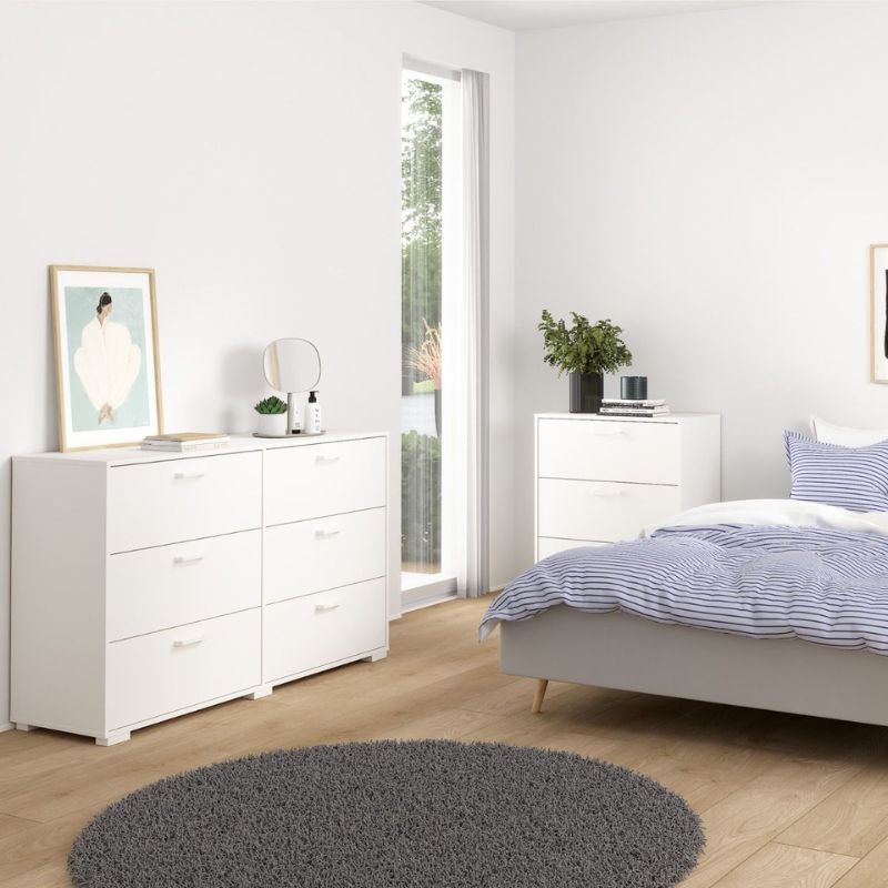Modern bedroom with white dresser, bed, and decor elements.