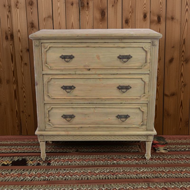 Vintage-style dresser with four drawers against a wooden wall.