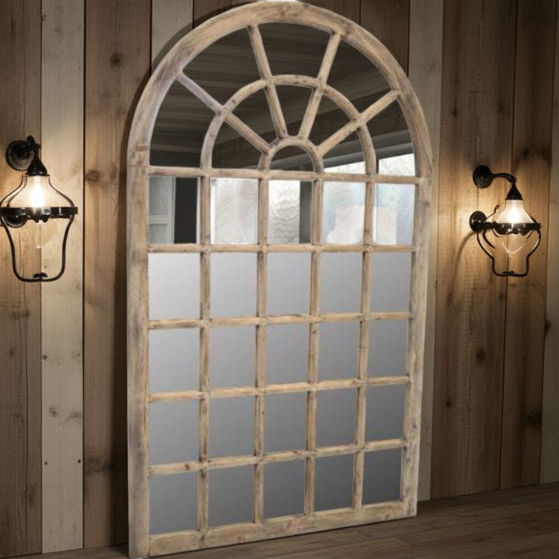 Large arched mirror with wooden frame on a wooden wall with sconces.