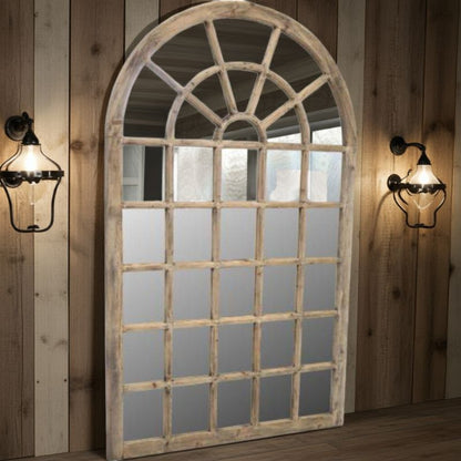 Large arched mirror with wooden frame on a wooden wall with sconces.