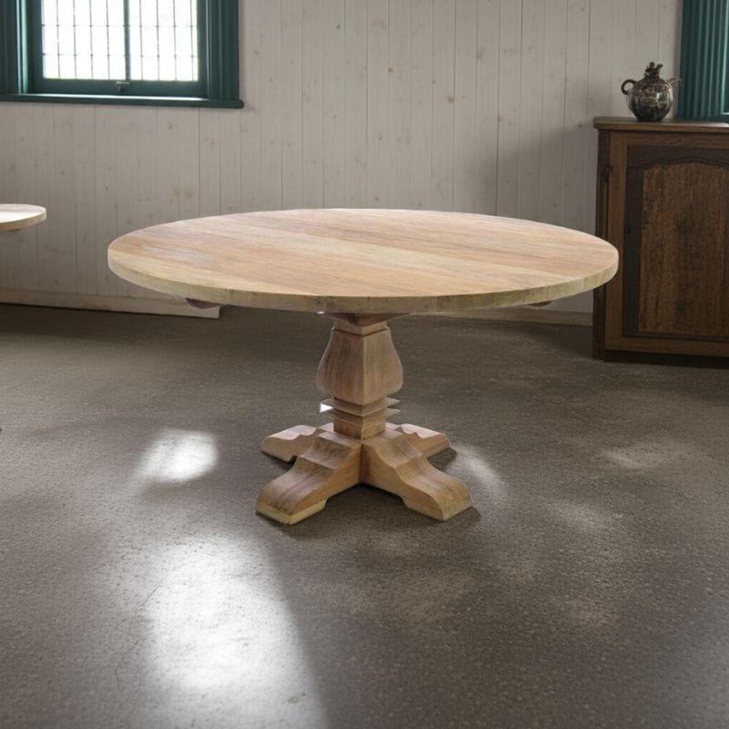 Round wooden table with a pedestal base in a room with concrete floor and wooden wall.