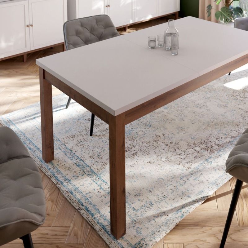 Extending white Dining table with wooden legs and white top in a room with chairs and a rug.