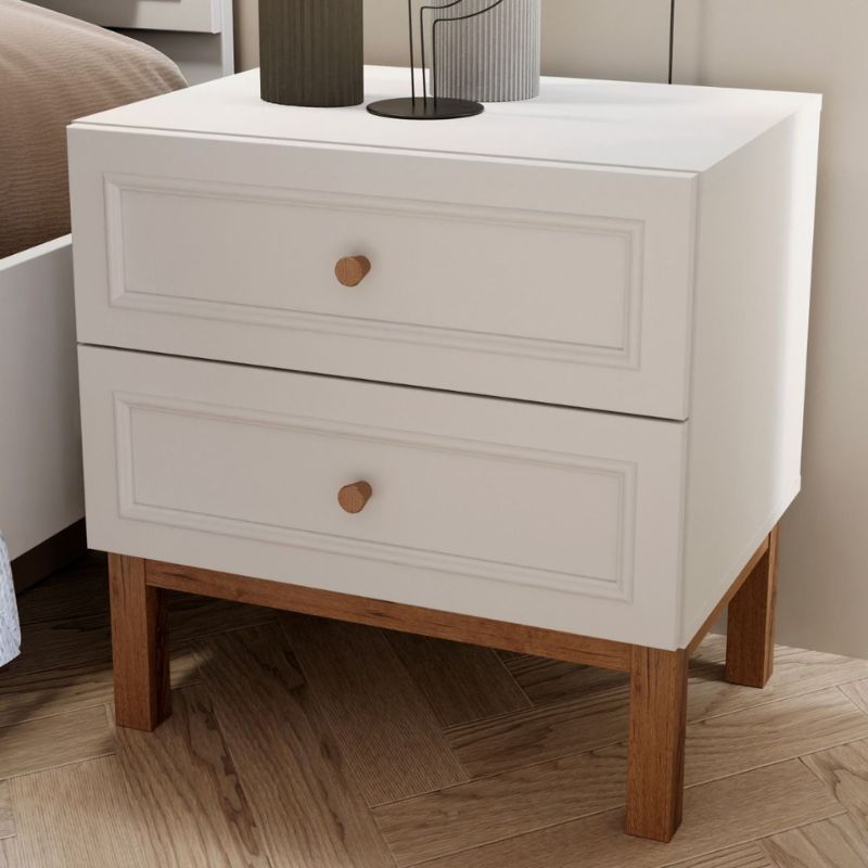 White nightstand with wooden legs in a bedroom setting