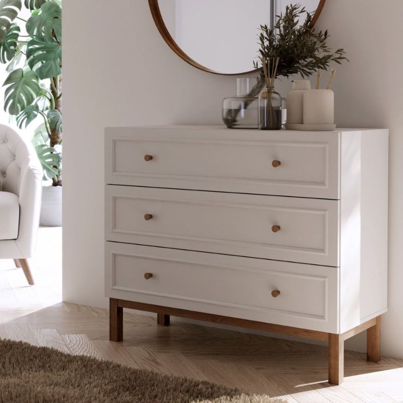 White dresser with wooden legs in a room with a mirror and plants