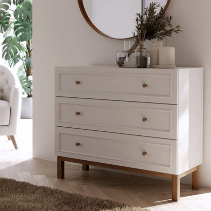 White dresser with wooden legs in a room with a mirror and plants
