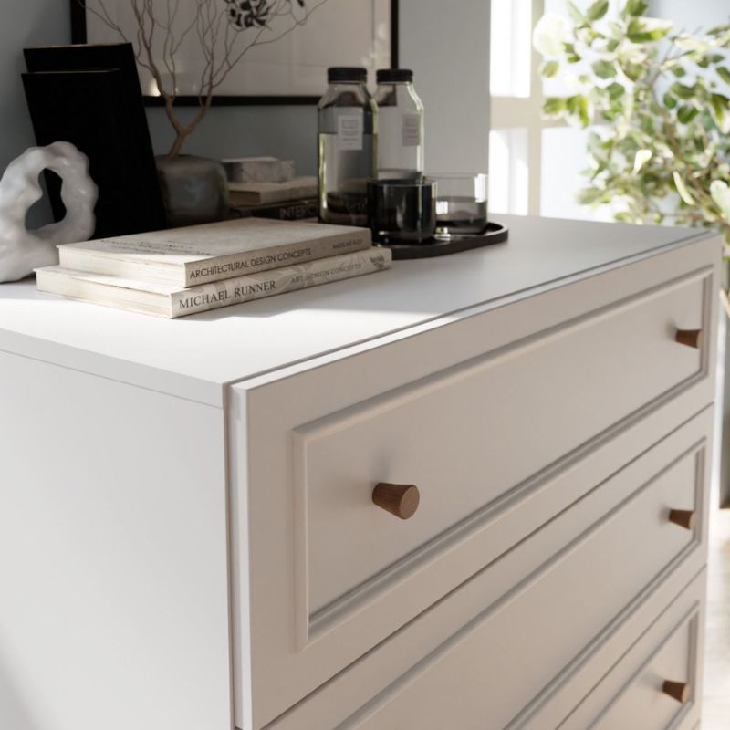 White dresser with wooden knobs featuring books and decorative items.