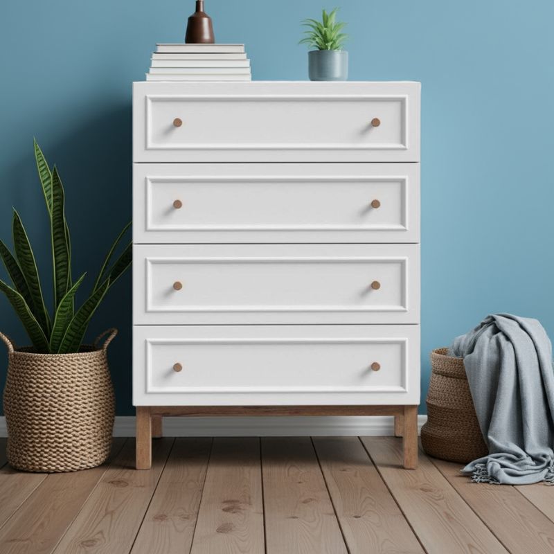 White dresser with wooden feet against a blue wall with decorative items on top.