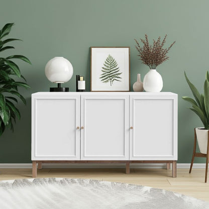 White sideboard with 3 doors with decorative items against a green wall